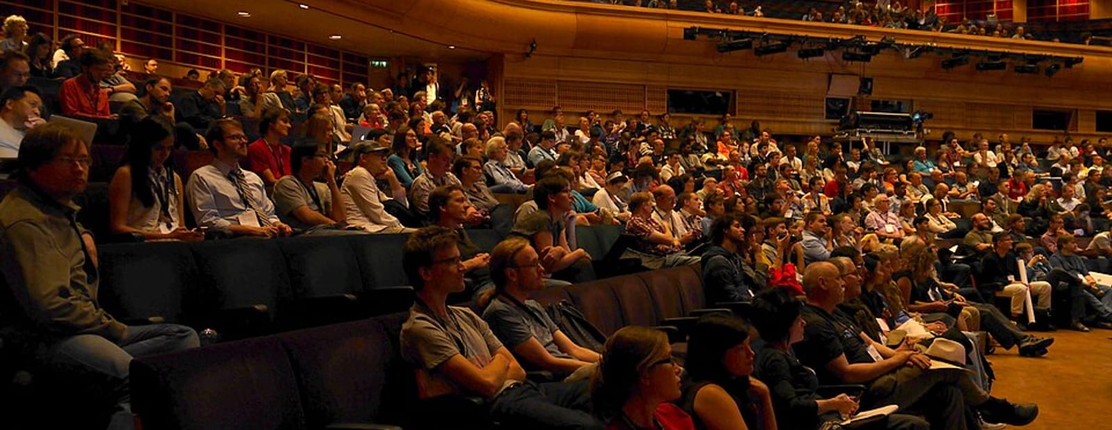 Plateia lotada em um auditório durante uma palestra
